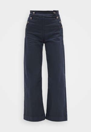 Námořnicky modré kalhoty s vysokým pasem a širokými nohavicemi, zdobené stříbrnými knoflíky po stranách a hladkou, texturovanou látkou.