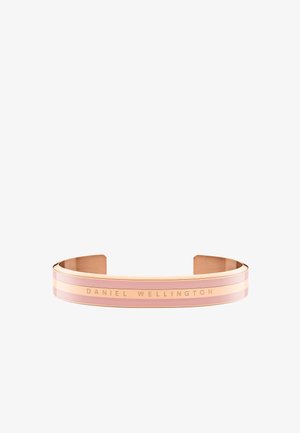 Rózsaarany csuklószorító, sima felülettel, rózsaszín és arany csíkos díszítéssel, valamint a "DANIEL WELLINGTON" felirattal gravírozva a sávon.