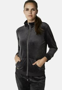 Zwarte velours zip-up jas met hoge kraag, geribbelde manchetten en zakken, met een gladde textuur en een minimalistisch ontwerp.