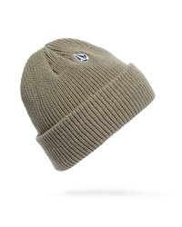 Beige gebreide beanie met omgeslagen rand en klein zwart-wit logo-embleem aan de zijkant op een witte achtergrond.