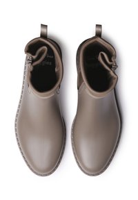Botas de tobillo de goma marrón con un acabado suave, punta redonda y cremallera lateral. Asa en la parte trasera para facilitar el calzado. La suela texturizada resalta la tracción.