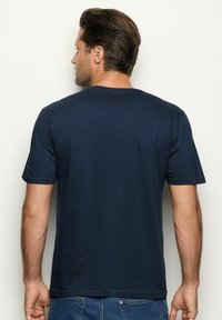 Námořnická modrá tričko s krátkým rukávem a kulatým výstřihem, vyrobené z měkké látky. Jednoduchý design bez viditelných vzorů nebo akcentů.