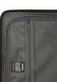 Interno di una valigia nera che presenta un comparto con zip dotato di un pannello in rete. Il materiale ha una superficie liscia con sottili motivi a righe e un'etichetta.