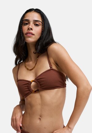 Brązowy prążkowany top bikini z okrągłym akcentem z żółwia na środku, cienkimi regulowanymi ramiączkami i fakturowaną powierzchnią.
