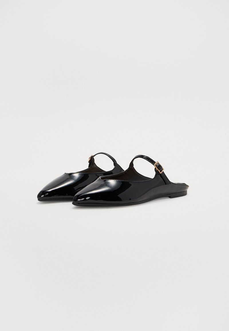 Chaussures slingback en cuir verni noir avec des bouts pointus, une bride ajustable à la cheville et une semelle plate. Texture lisse avec un minimum de détails.