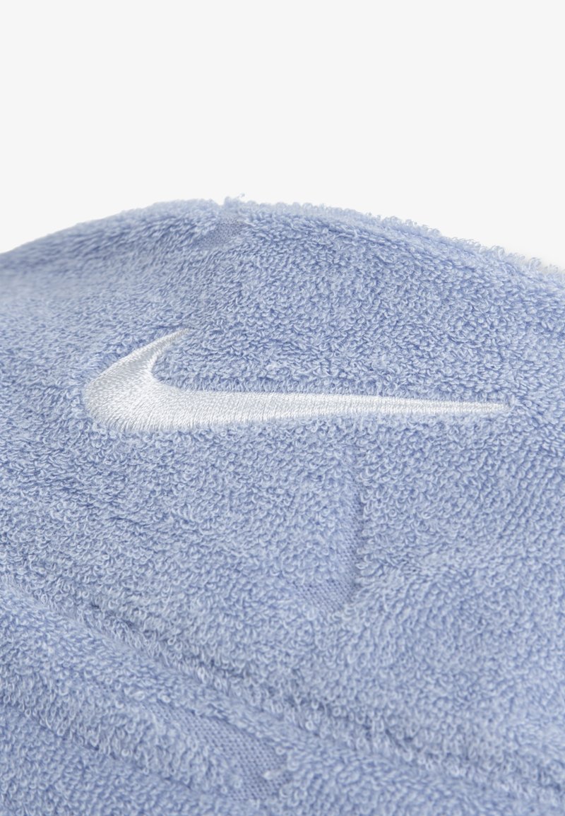 Hellblaues Handtuch aus Frottee mit weißem Nike-Swoosh-Logo, das auf dem Stoff gestickt ist.