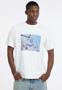 Witte katoenen t-shirt met een grafische print van een basketballer in de lucht, met blauwe en rode accenten in het ontwerp. Casual pasvorm.
