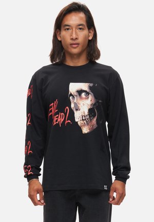 T-shirt noir à manches longues présentant un graphisme de crâne et le texte "Evil Dead 2" en rouge, avec des accents imprimés sur les manches.