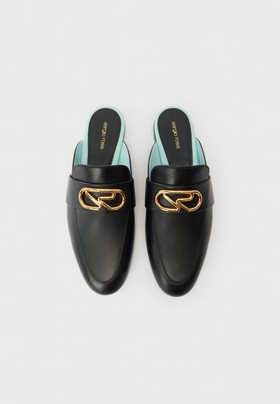 Mocasini negri din piele, slip-on, cu detaliu din lanț auriu în partea de sus și branțuri de un albastru deschis, așezați unul lângă altul pe un fundal alb.