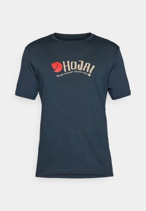 Tricou bleumarin din material ușor, cu un logo ce prezintă un grafic al unui vulpe roșie și textul "HOJA! ECHIPAMENTE DE CICLISM FJÄLLRÄVEN SUEDIA."