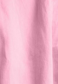 Tissu rose clair avec une texture lisse, présentant des plis subtils et un aspect transparent. Convient pour les vêtements ou la décoration intérieure.