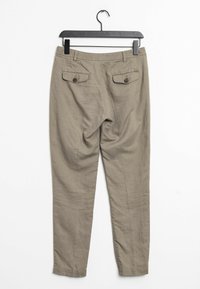 Světlé khaki kalhoty s hladkým povrchem, vybavené dvěma zadními kapsami se zapínáním na knoflíky a s rovným střihem. Zavěšené na černém ramínku.