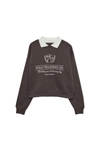 Mørkebrun langærmet sweatshirt med hvid krave, med en hvid polo-spiller logo og teksten "POLO TRAINING CO. Udfordr dine grænser hver dag".