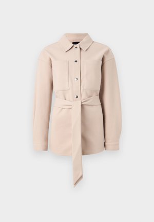 Camisa de color beige claro con cinturón, cuello tipo camisa, cierre de botones en la parte delantera, dos bolsillos en el pecho y mangas largas. Textura suave, diseño minimalista.