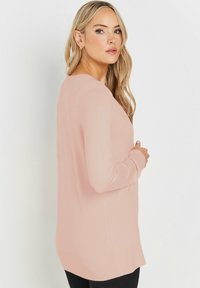 Maglione a maniche lunghe di un delicato rosa, con una vestibilità comoda, caratterizzato da un collo rotondo e un orlo a coste, realizzato in materiale morbido e elasticizzato.