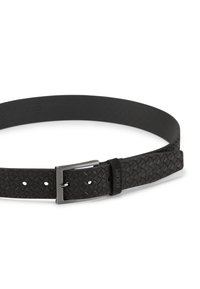 Zwarte geweven leren riem met een gladde zwarte binnenkant, een zilveren metalen gesp en een leren accent met merk. Voorzien van meerdere aanpassingsgaten.