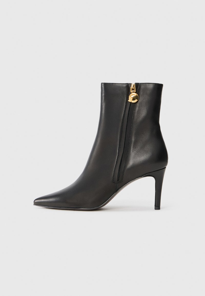 Bottine noire en cuir avec un bout pointu, un talon haut élancé et une fermeture éclair sur le côté, arborant une touche dorée au tirette de la fermeture.