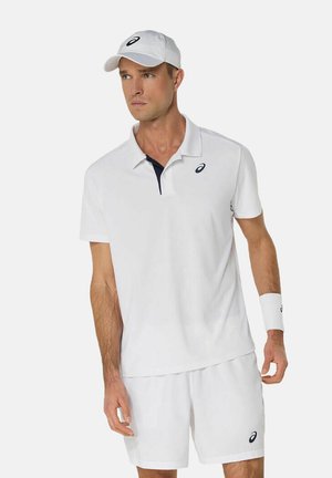 Weißes Tennis-Outfit, bestehend aus einem Poloshirt mit Kragen und marineblauen Akzenten, passenden Shorts und einer weißen Kappe mit Logo. Enthält ein weißes Handgelenkband.