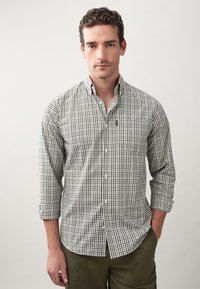 Hemd mit Knopfleiste, grün-navy kariert, langärmlig und mit Kragen. Aus Baumwolle gefertigt. Auffälliges Logo auf der Brust.