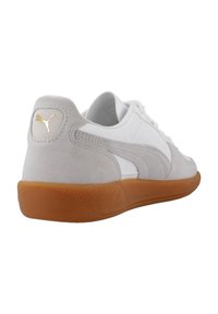 Białe sneakersy z szarymi akcentami z zamszu, gumową podeszwą i złotym logo. Posiadają zaokrąglony kształt i zapięcie na sznurowadła. Widoczne teksturowane boczne panele.