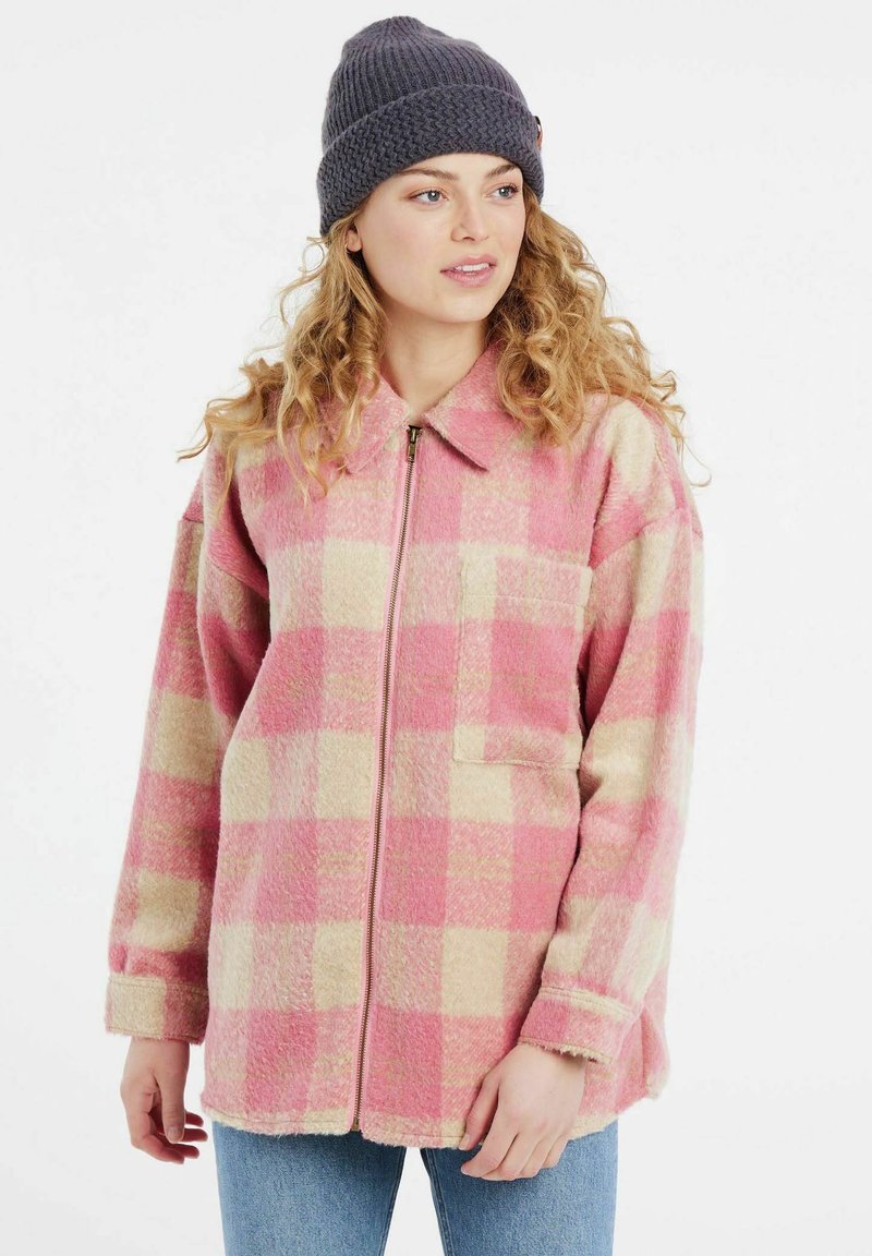Chaqueta de felpa a cuadros en rosa y crema con cuello y cremallera delantera, que presenta un bolsillo de parche y mangas largas. Llevada sobre denim.