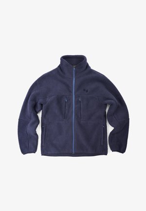 Fleece jacket in navy with a high collar, zip front, and two zippered chest pockets. Features contrasting blue zippers and a soft texture.