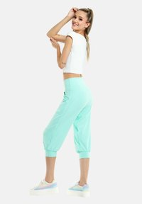 Letvægtige lysegrønne cropped joggers med elastiske manchetter, sidelommer og høj talje, parret med pastelfarvede platform sneakers.