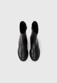 Sorte skinn ankle boots med en glatt tekstur, runde tær og gummisåle. Har en glidelås på siden for enkel påkledning.