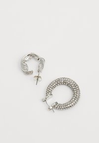 Sudraba riņķveida auskari: viens ar teksturētu dizainu, bet otrs pilnībā rotāts ar caurspīdīgiem rhinestones, ar stiprinājumiem un aizdares mehānismu.