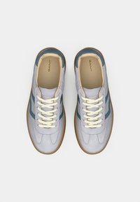 Ανοιχτό γκρι αθλητικά παπούτσια με μπλε λεπτομέρειες, υφασμάτινο επάνω μέρος με υφή, κρέμ κορδόνια και καφέ λαστιχένια σόλα. Λογότυπο "GANT" στη γλώσσα.