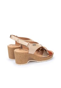 Sandalias de cuña de corcho con tiras cruzadas en beige, marrón y cobre. Parte superior de cuero suave con diseño de talón al descubierto y detalles texturizados.