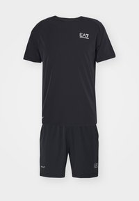 Čierny športový outfit, ktorý pozostáva z trička s krátkym rukávom a zodpovedajúcich šortiek, vyrobený z hladkej, ľahkej tkaniny, s akcentmi značky.