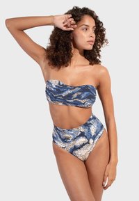 Bikiny set s vysokým pásom v modro-krémovom vlnkovanom vzore. Obsahuje top bez ramienok a výrez na bokoch. Vyrobené z hladkej tkaniny.