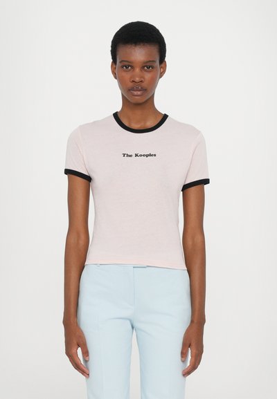 Világos rózsaszín, rövid ujjú póló fekete bordás gallérral és ujjakra, a mellrészen fekete színben a "The Kooples" logóval.