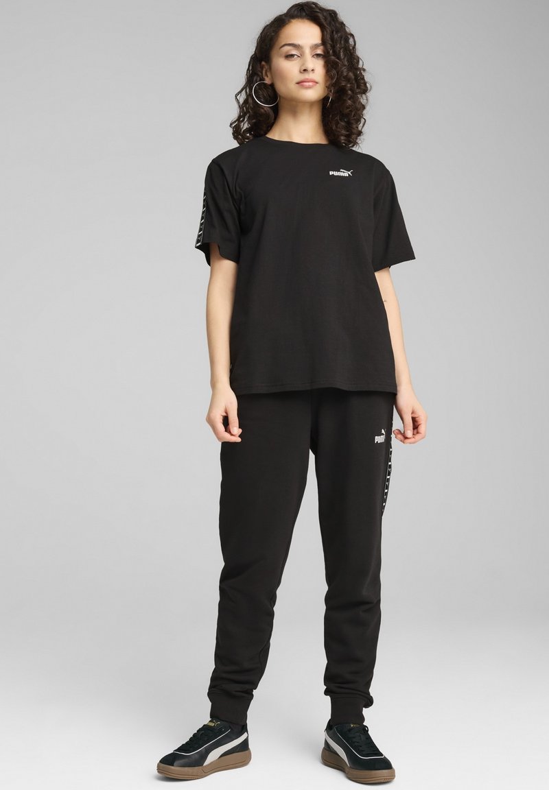 Camiseta de algodón negra y pantalones a juego, con el logo de PUMA, corte relajado y una marca sutil a lo largo del lado de los pantalones. Incluye zapatillas.