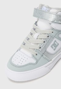 Mintgrüner High-Top-Sneaker mit weißem Akzent, strukturiertem grauen Riemen, perforierter Zehenpartie und auffälligem Logo-Detail an der Seite.