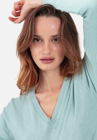 Pull col V vert menthe clair en tissu tricoté doux, avec détails côtelés et coupe décontractée, manches longues et texture subtile.