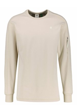 Hellbeige Langarmshirt aus strukturiertem Stoff, mit geripptem Kragen und Bündchen, ausgestattet mit einer Reißverschlusstasche am linken Arm.