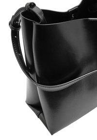 Czarna skórzana torba typu tote o gładkiej fakturze, wyraźnie ukształtowanym kształcie i złożonym wierzchu, wyposażona w krótki uchwyt i minimalistyczne akcenty designu.