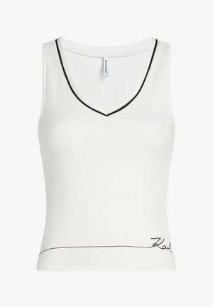 Bela rebrasta majica brez rokavov z V-izrezom, poudarjena s črnim trakom, z nežnim črnim podpisnim detajlom blizu roba.