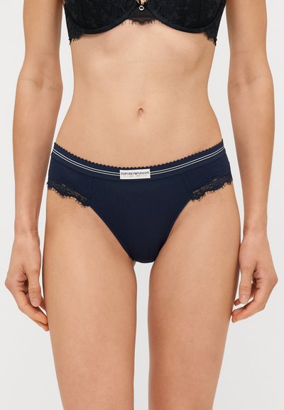 Marineblauwe katoenen bikini slipjes met kantafwerking; de elastische tailleband heeft een contrasterend gestreept detail en een logo label aan de voorkant.
