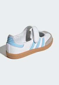 Biele kožené topánky s modrými a šedými akcentmi, so suchým zipsom a gumovou podrážkou. Na boku sú tri modré pruhy.