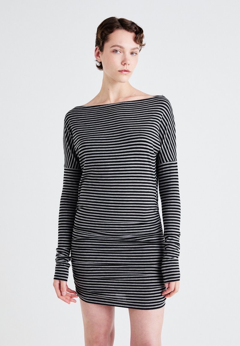 Gestreiftes langärmliges Kleid in Schwarz und Grau. Weicher Stoff, Bootsausschnitt, taillierte Silhouette und Daumenlöcher an den Bündchen. Glatte Textur.