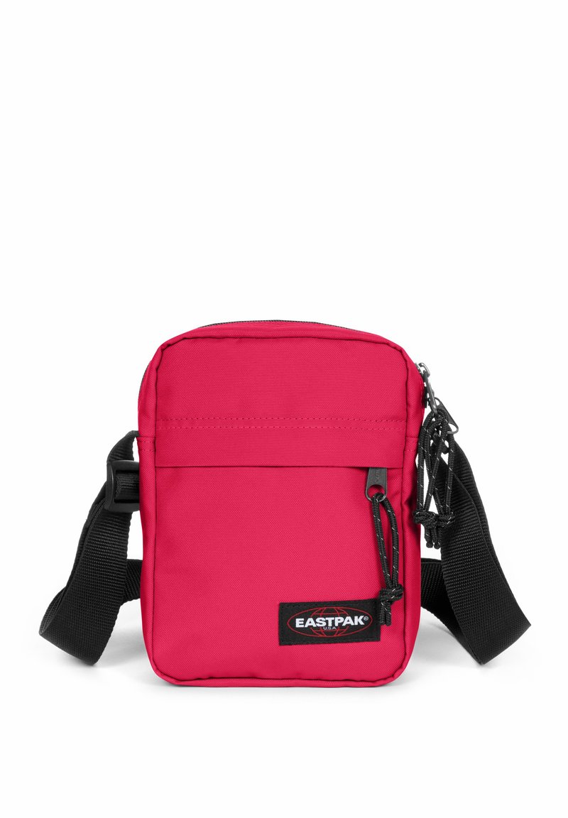 Borsa a tracolla di stoffa rossa con cinturino nero regolabile, chiusura con zip, tasca frontale e patch con il logo Eastpak. Texture liscia, forma rettangolare.