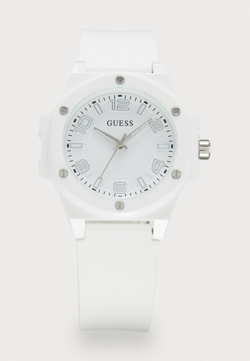 White silicone strap watch with round white face, silver hour markers, and 'GUESS' logo. Features a silver crown and textured case accents.