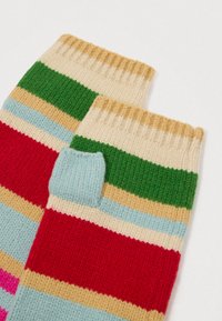 Knit fingerless gloves featuring horizontal stripes in red, green, blue, beige, and pink. Textured wool material with ribbed cuffs.