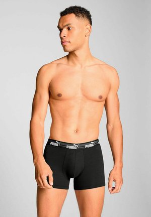 Black boxer shorts made of cotton, featuring an elastic waistband with white "PUMA" branding. Simple, fitted design with a mid-rise cut.