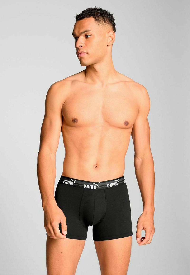 Black boxer shorts made of cotton, featuring an elastic waistband with white "PUMA" branding. Simple, fitted design with a mid-rise cut.