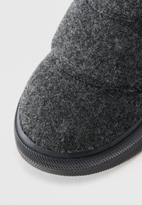 Grå slip-on sko i teksturert overdel, med avrundet tå og gummisåle med karakteristisk mønster.