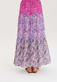 Maxi sukně s růžovým vzorovaným topem, přecházející na spodní část s barevným paisley vzorem. Hladká tkanina a elastický pas. Nosená s sandály.